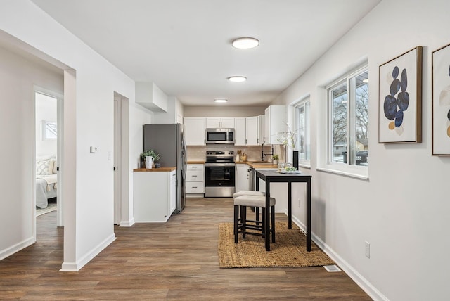 kitchen with hardwood / wood-style floors, butcher block countertops, white cabinetry, sink, and stainless steel appliances