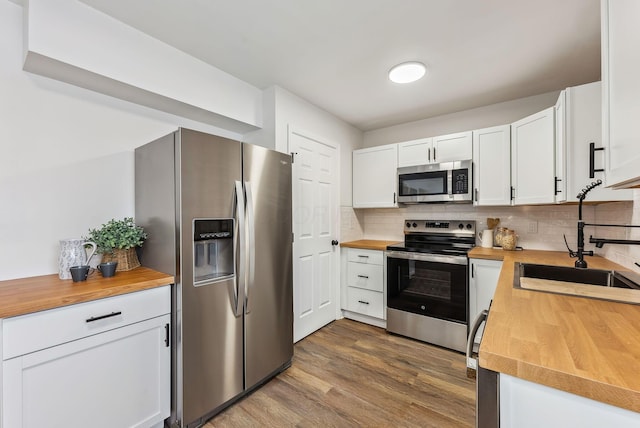 kitchen with sink, dark hardwood / wood-style floors, white cabinets, stainless steel appliances, and backsplash