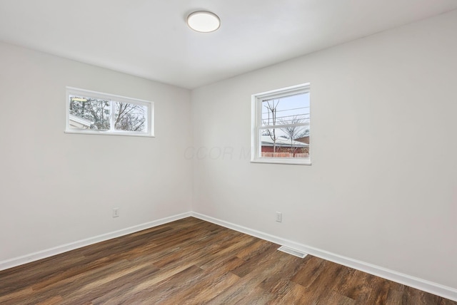 spare room with dark wood-type flooring and a healthy amount of sunlight