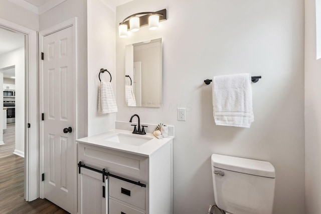 bathroom with hardwood / wood-style flooring, vanity, and toilet