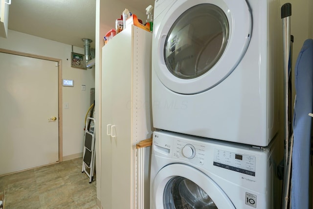 clothes washing area featuring stacked washing maching and dryer