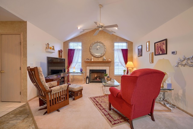 living room with ceiling fan, a healthy amount of sunlight, a tiled fireplace, and vaulted ceiling