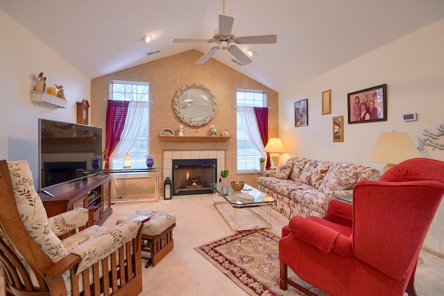 carpeted living room with ceiling fan, vaulted ceiling, and a tile fireplace