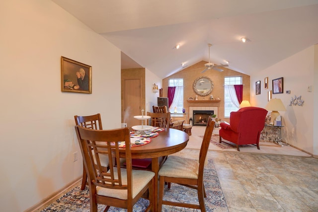 dining area with vaulted ceiling, ceiling fan, and a fireplace