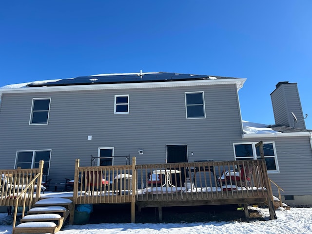 snow covered back of property featuring a wooden deck