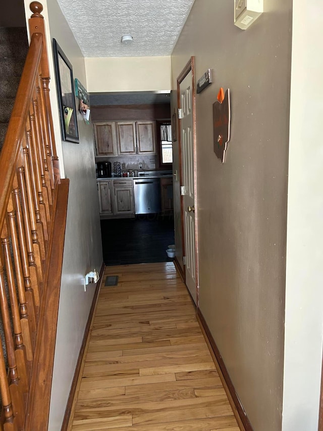 corridor with light hardwood / wood-style floors and a textured ceiling