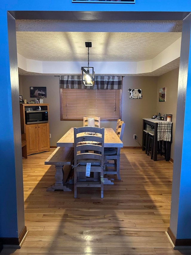 dining room featuring wood-type flooring and a textured ceiling