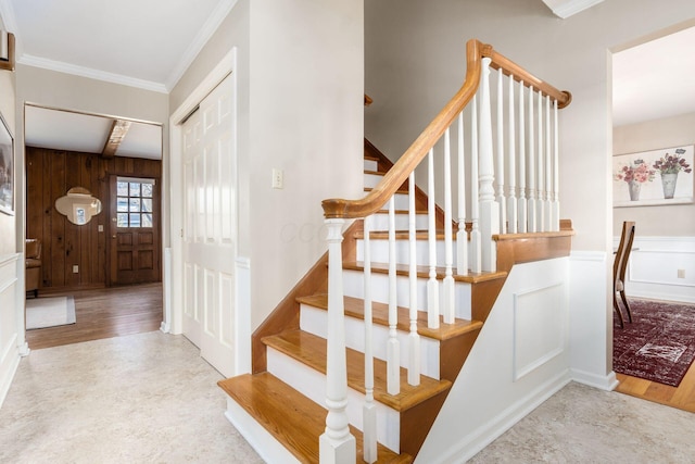 stairway featuring hardwood / wood-style flooring, ornamental molding, and wooden walls