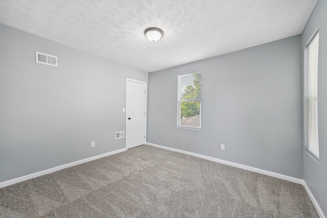 carpeted spare room with a textured ceiling