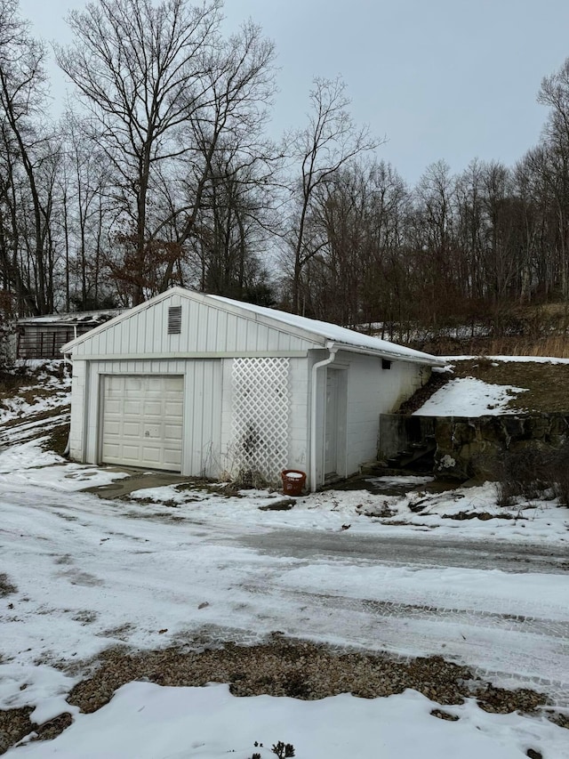 snow covered structure featuring a garage