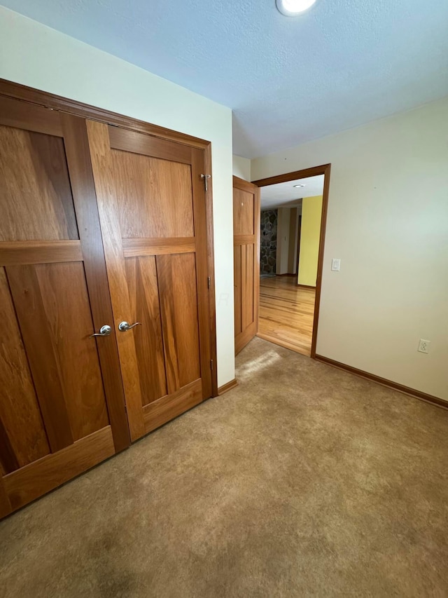 unfurnished bedroom with light carpet, a closet, and a textured ceiling