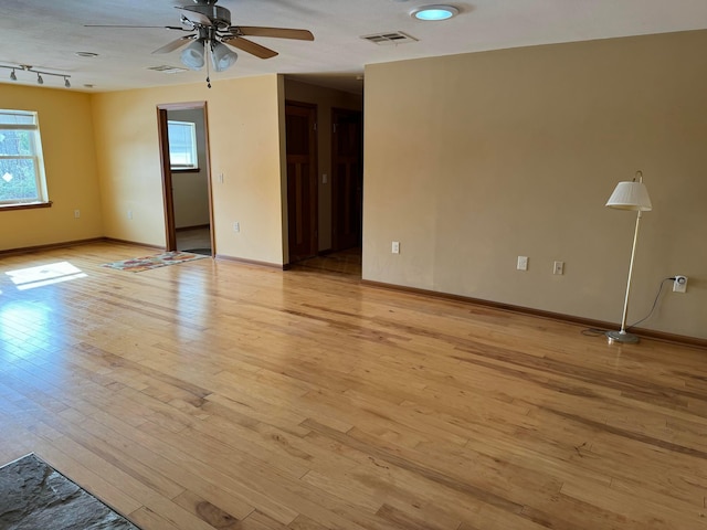 empty room featuring ceiling fan, track lighting, and light wood-type flooring