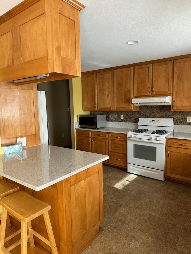 kitchen featuring light stone counters, backsplash, white appliances, and a breakfast bar area