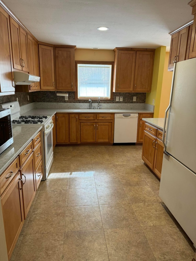 kitchen featuring sink, white appliances, and backsplash