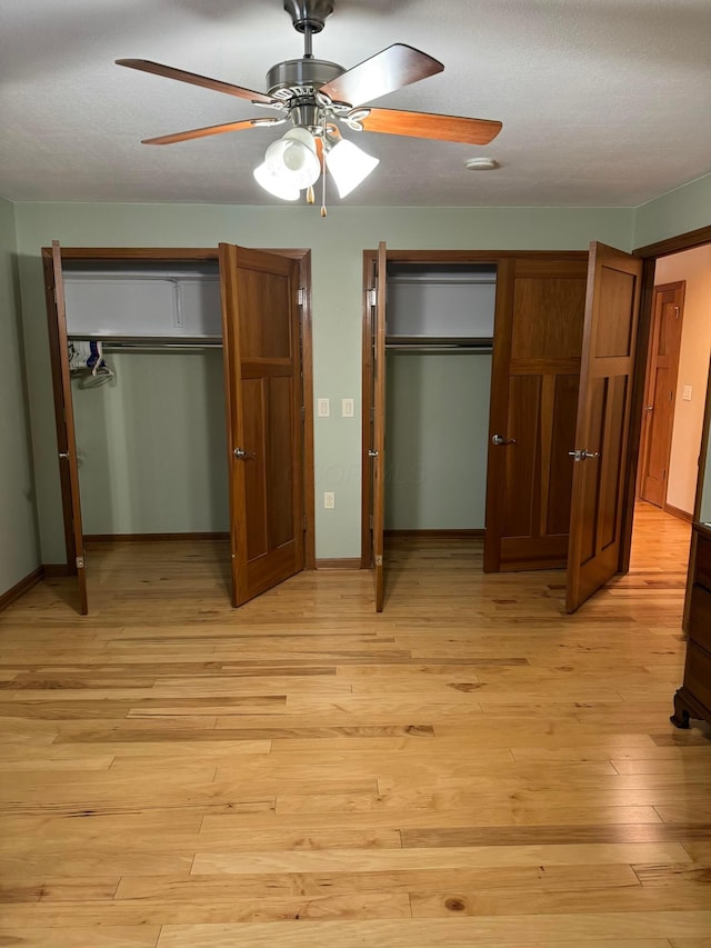 unfurnished bedroom with ceiling fan, light hardwood / wood-style floors, and multiple closets