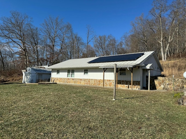 back of property with a yard and solar panels