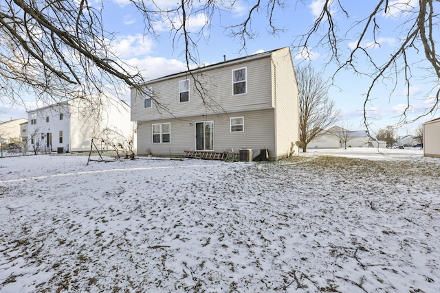 snow covered rear of property featuring central AC