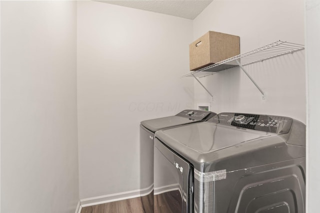 laundry room featuring wood-type flooring, separate washer and dryer, and a textured ceiling