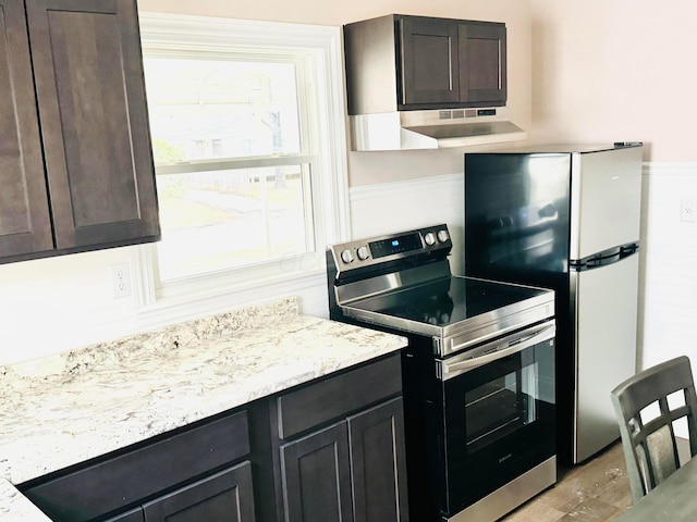 kitchen featuring stainless steel appliances, light stone countertops, and dark brown cabinets