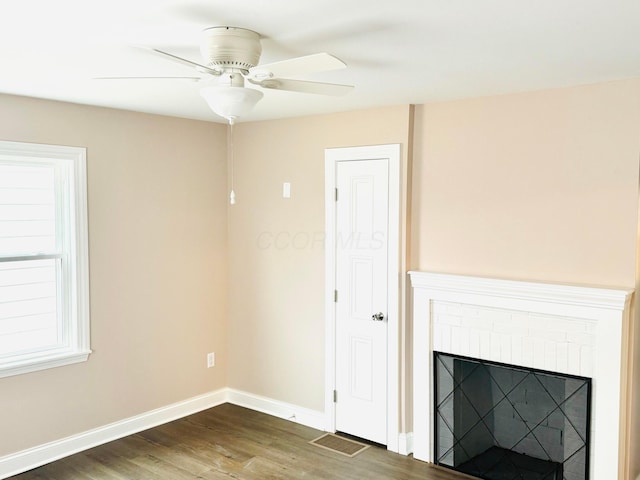 unfurnished living room with ceiling fan, a brick fireplace, and dark hardwood / wood-style flooring