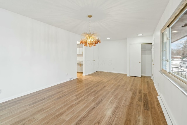 interior space with a baseboard heating unit, a notable chandelier, and light wood-type flooring