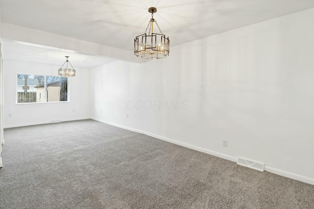 carpeted empty room featuring a chandelier