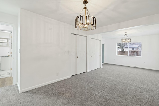 spare room with carpet and a notable chandelier