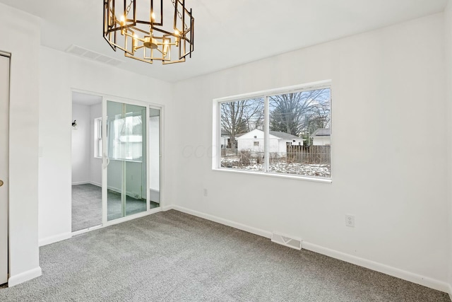 carpeted spare room with a chandelier