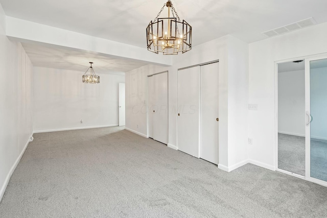 carpeted spare room with an inviting chandelier