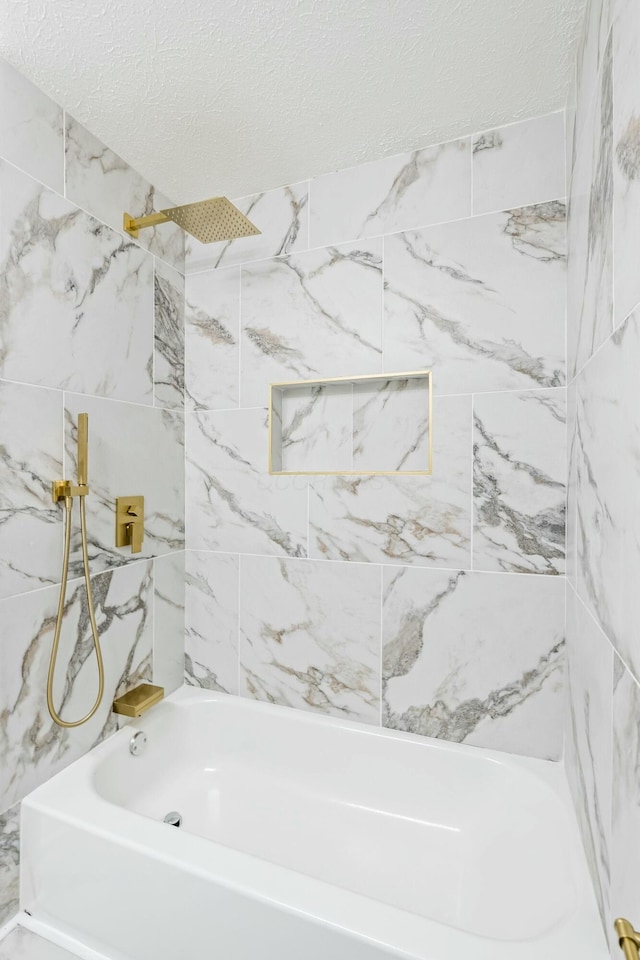 bathroom with tiled shower / bath and a textured ceiling