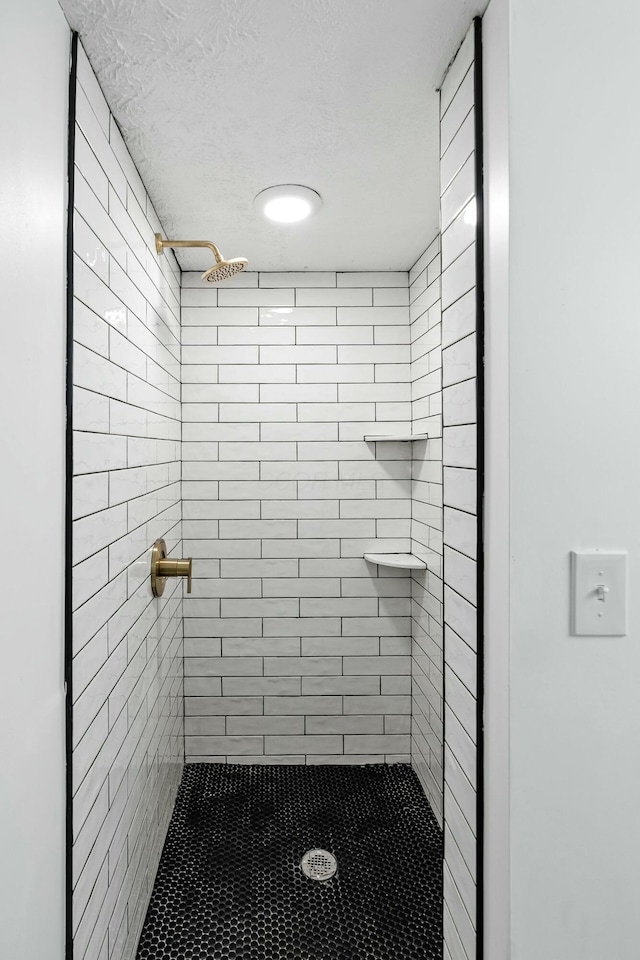 bathroom with a textured ceiling and a tile shower