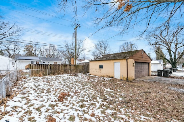 yard covered in snow featuring a garage and an outbuilding