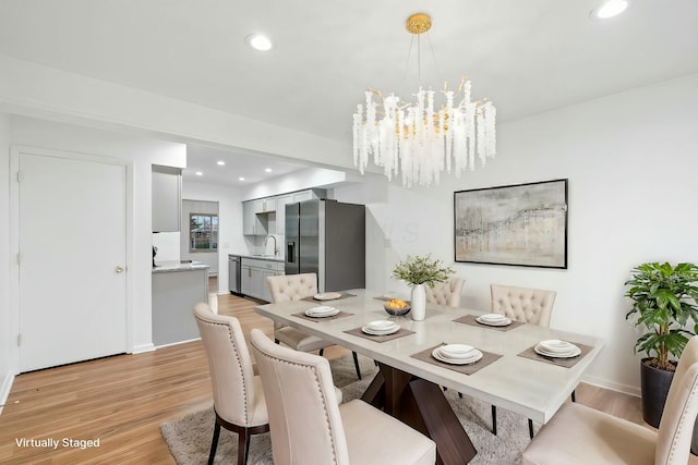 dining room with sink, a notable chandelier, and light hardwood / wood-style floors