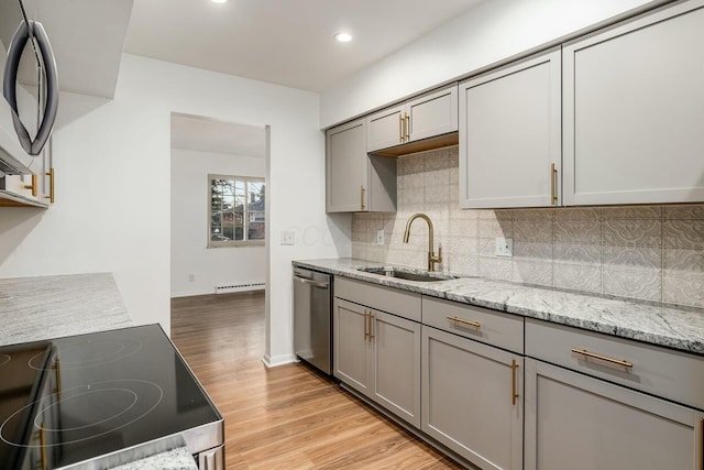 kitchen featuring sink, gray cabinetry, light stone counters, appliances with stainless steel finishes, and light hardwood / wood-style floors