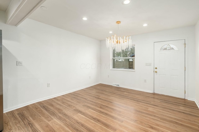 entrance foyer featuring beamed ceiling, a chandelier, and light wood-type flooring