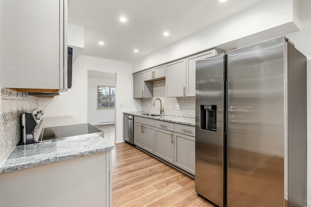 kitchen featuring sink, gray cabinetry, light stone counters, stainless steel appliances, and light hardwood / wood-style floors