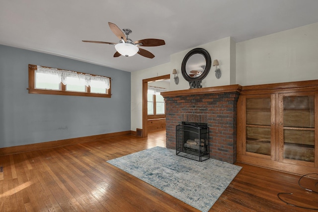 living room featuring ceiling fan, hardwood / wood-style floors, and a brick fireplace