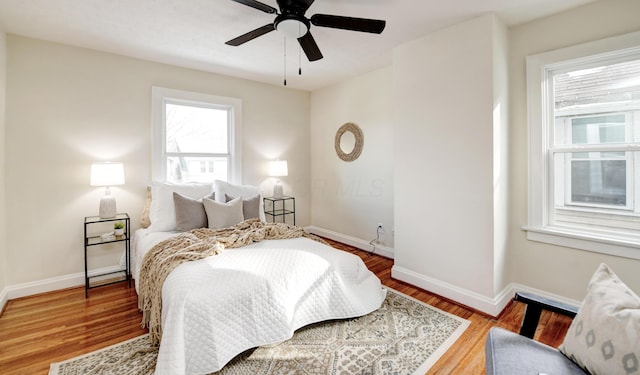 bedroom with ceiling fan, hardwood / wood-style floors, and multiple windows