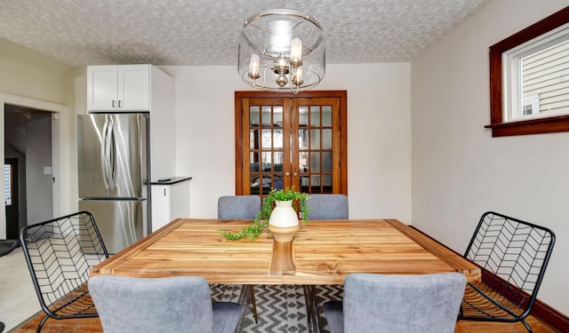 dining space with a notable chandelier, a textured ceiling, and french doors