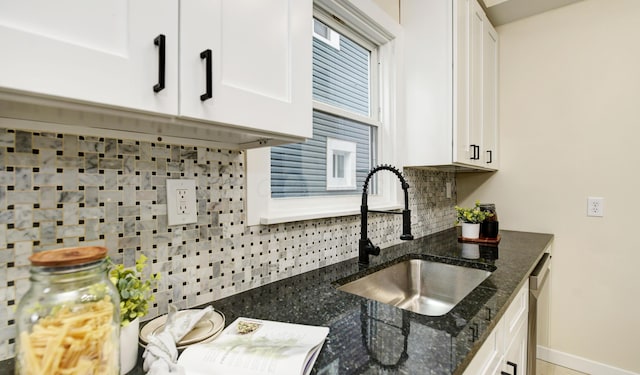 kitchen featuring dishwasher, sink, white cabinets, decorative backsplash, and dark stone counters