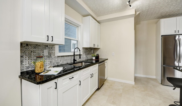 kitchen with sink, white cabinetry, a textured ceiling, dark stone counters, and stainless steel appliances