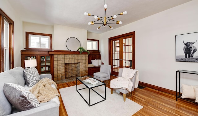 living room with hardwood / wood-style flooring, a tile fireplace, french doors, and a chandelier