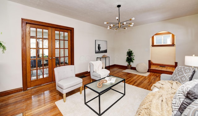 living room with hardwood / wood-style floors, a notable chandelier, and french doors