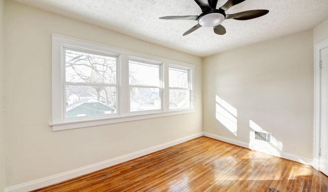 spare room with plenty of natural light, a textured ceiling, and light wood-type flooring