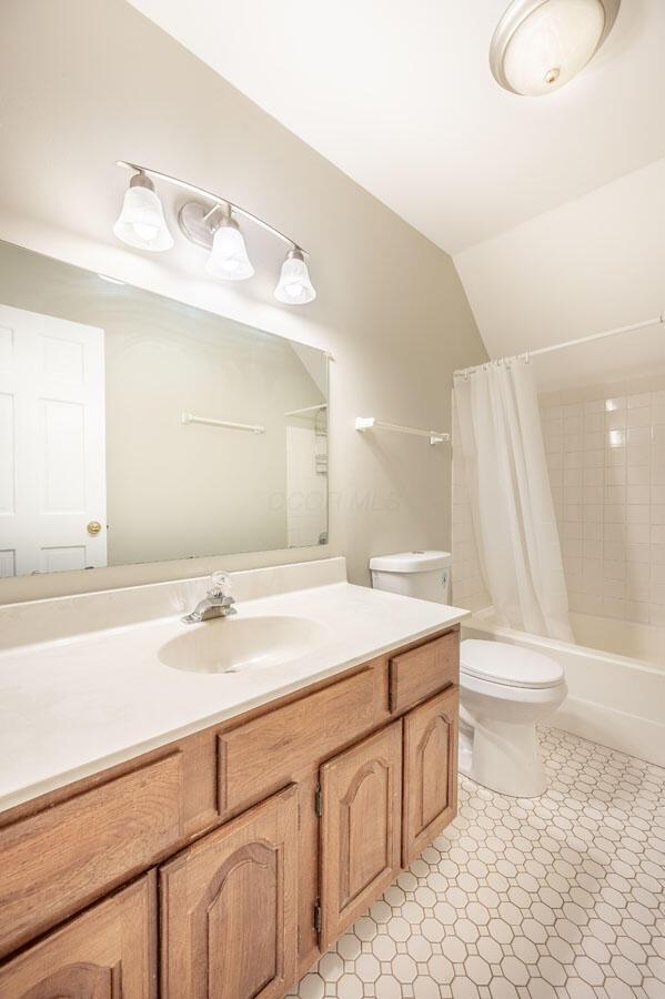 full bathroom with toilet, lofted ceiling, vanity, and shower / bathtub combination with curtain