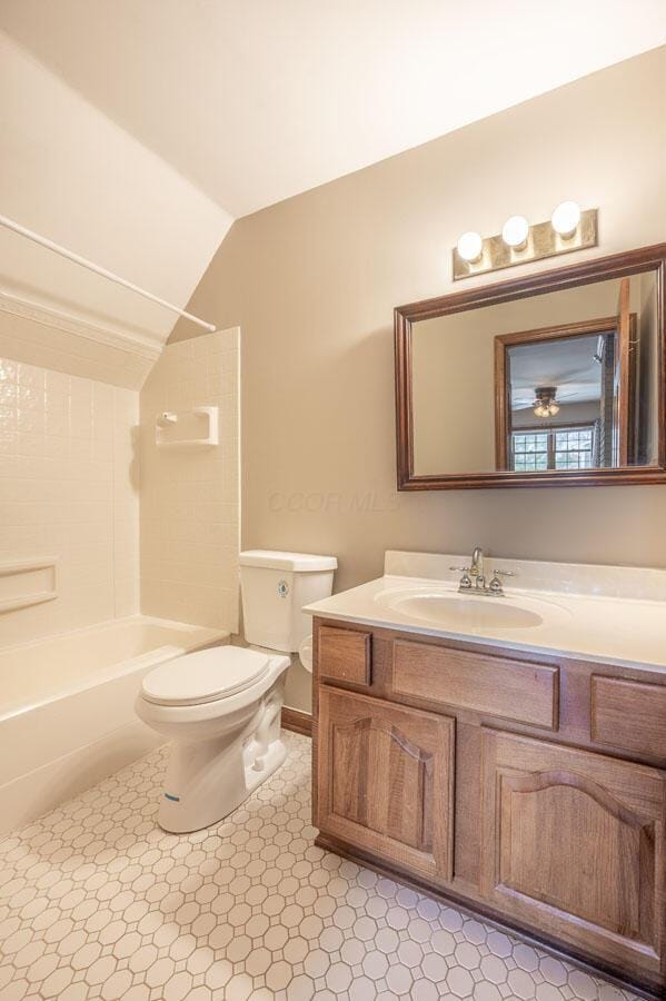 full bathroom with tile patterned floors, lofted ceiling, toilet,  shower combination, and vanity