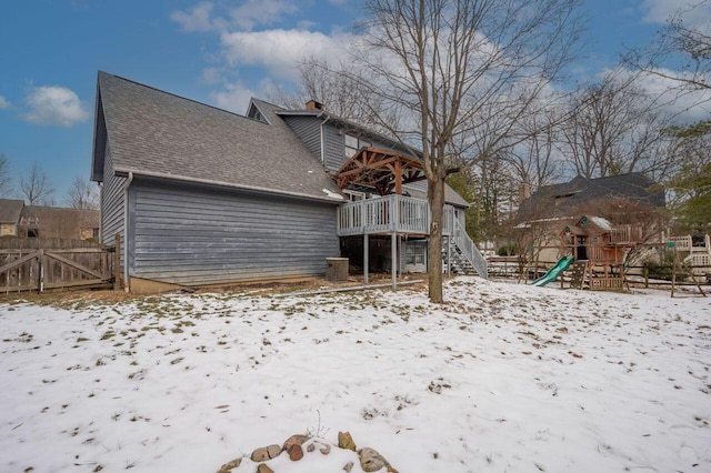 snow covered rear of property featuring a playground