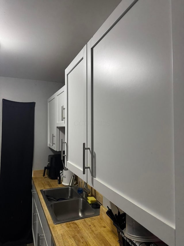 kitchen featuring hardwood / wood-style flooring, white cabinetry, and sink