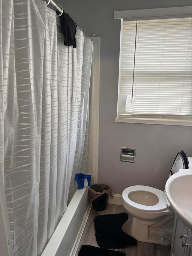 full bathroom with shower / tub combo, sink, hardwood / wood-style floors, and toilet