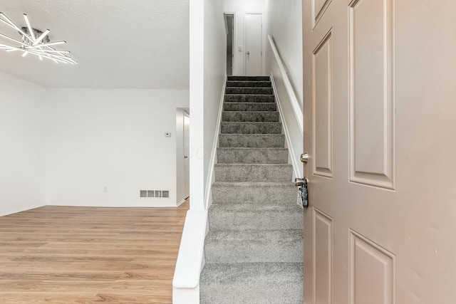 stairs with hardwood / wood-style floors and a textured ceiling